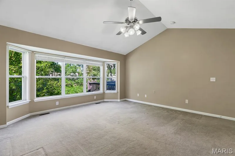 Double door entry -Vaulted ceiling primary Bedroom Suite featuring a wide 5 bay window, neutral wall tones, grey carpeting, and a ceiling fan with integrated lighting and massive walk in closet — 1103 Panda Court, Wentzville, MO 63385