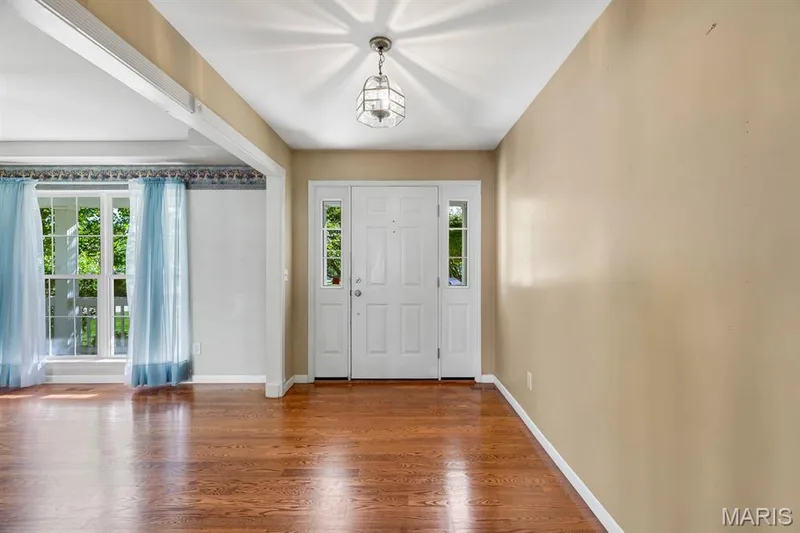 Entryway featuring a white door with sidelight windows, a hanging lantern light fixture, and wood-finish flooring — 1103 Panda Court, Wentzville, MO 63385