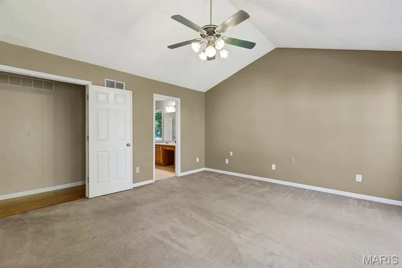 Double door entry -Vaulted ceiling primary Bedroom Suite featuring a wide bay window, neutral wall tones, grey carpeting, and a ceiling fan with integrated lighting and massive walk in closet — 1103 Panda Court, Wentzville, MO 63385