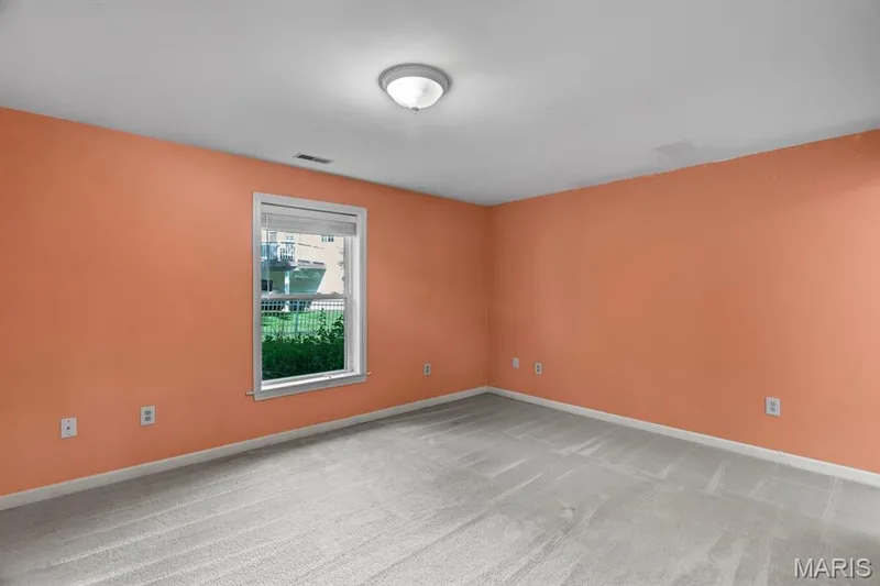 Carpeted interior space featuring a window with white trim, a flush-mount ceiling light, and light peach walls — 1103 Panda Court, Wentzville, MO 63385