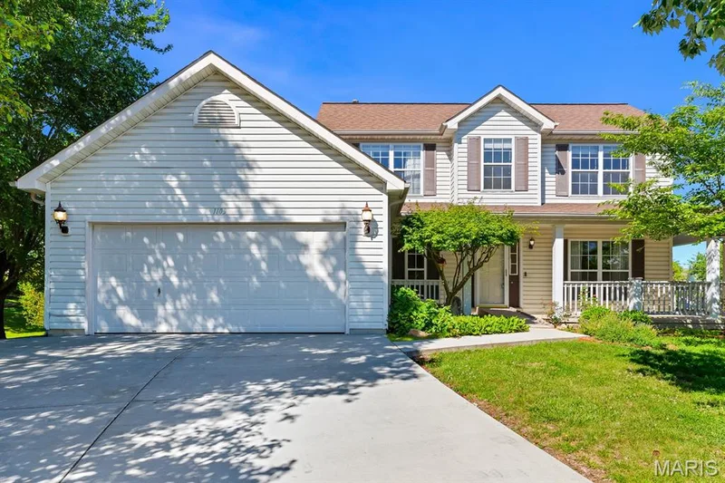 Two-story residence featuring light-toned siding, a covered front porch, and an attached two-car garage — 1103 Panda Court, Wentzville, MO 63385