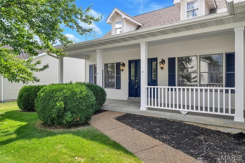 Covered front porch with white railing, blue shutters, and double entry doors — 195 England Drive, O'Fallon, MO 63366