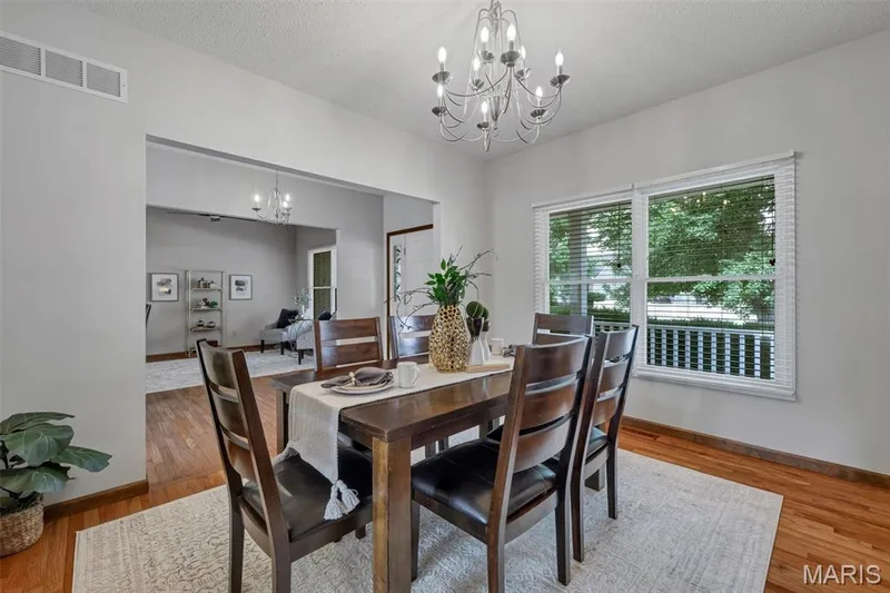 Dining area featuring a contemporary chandelier and wood-finish flooring — 195 England Drive, O'Fallon, MO 63366