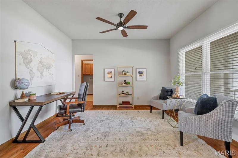 Spacious room featuring wood-finish flooring, a ceiling fan, and large windows with blinds — 195 England Drive, O'Fallon, MO 63366