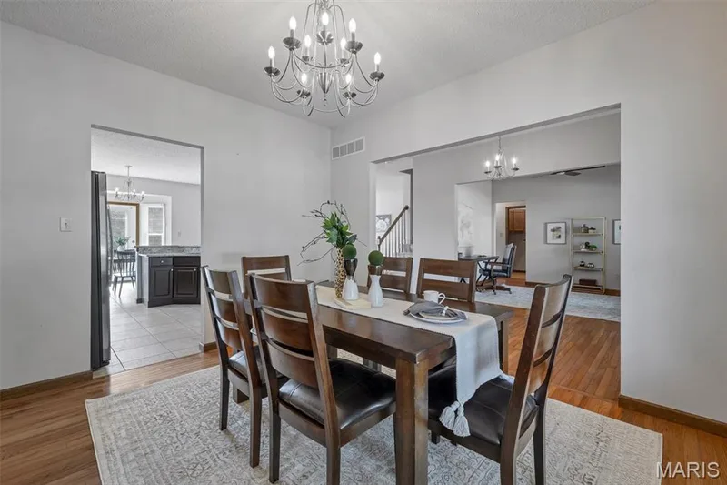 Dining area featuring wood-finish flooring, a contemporary chandelier, and a decorative area rug — 195 England Drive, O'Fallon, MO 63366