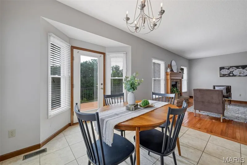 Dining area featuring a bay window with multiple vertical blinds and a glass-paneled door — 195 England Drive, O'Fallon, MO 63366