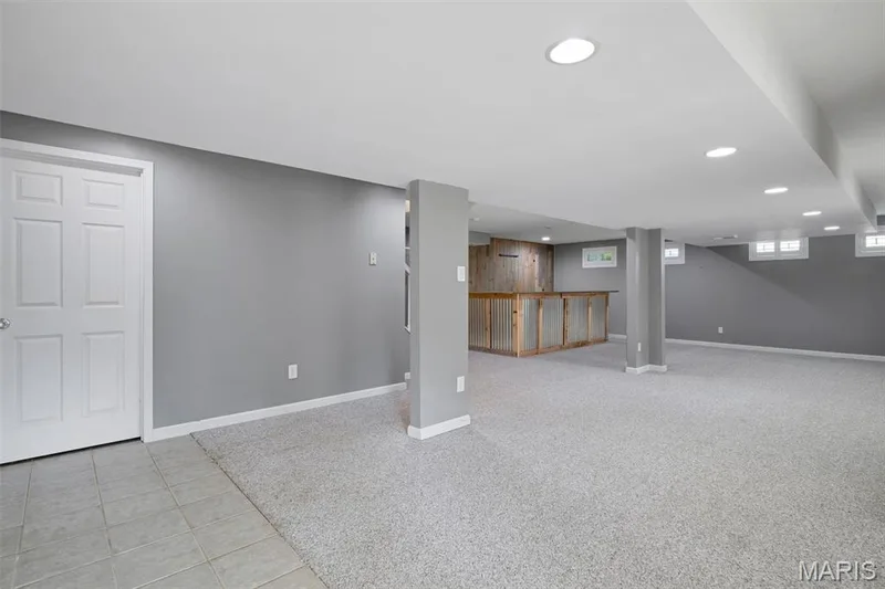 Spacious finished lower level featuring recessed lighting, a built-in bar with wood-finish paneling, gray painted walls, and light-colored carpeting — 195 England Drive, O'Fallon, MO 63366