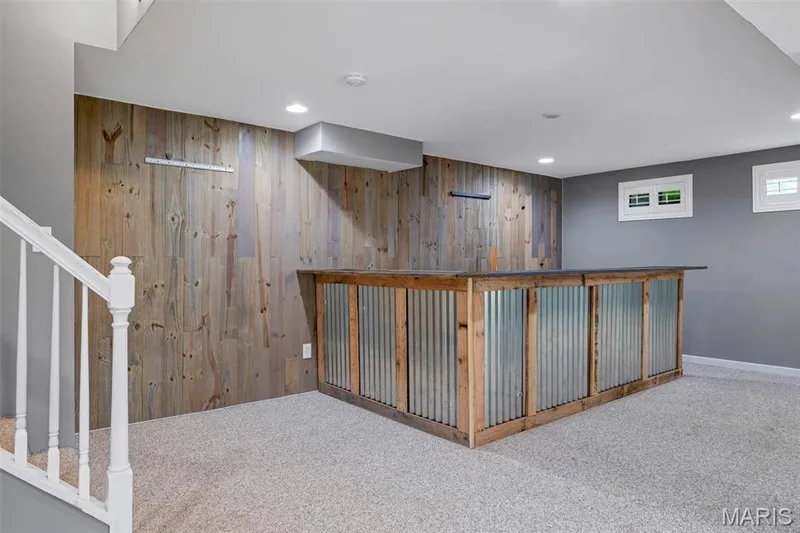 Custom bar featuring a corrugated metal and wood frame, set against a wood-paneled accent wall — 195 England Drive, O'Fallon, MO 63366