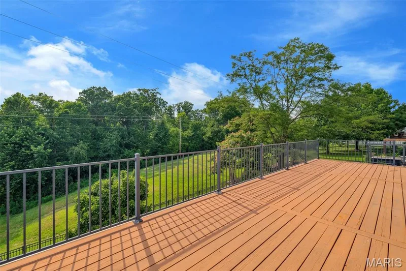 Expansive outdoor deck featuring wood-finish flooring and durable metal railings — 195 England Drive, O'Fallon, MO 63366