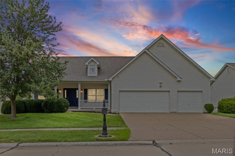 Ranch-style residence featuring a covered porch with white railing, a two-car garage, and dormer window detail — 195 England Drive, O'Fallon, MO 63366