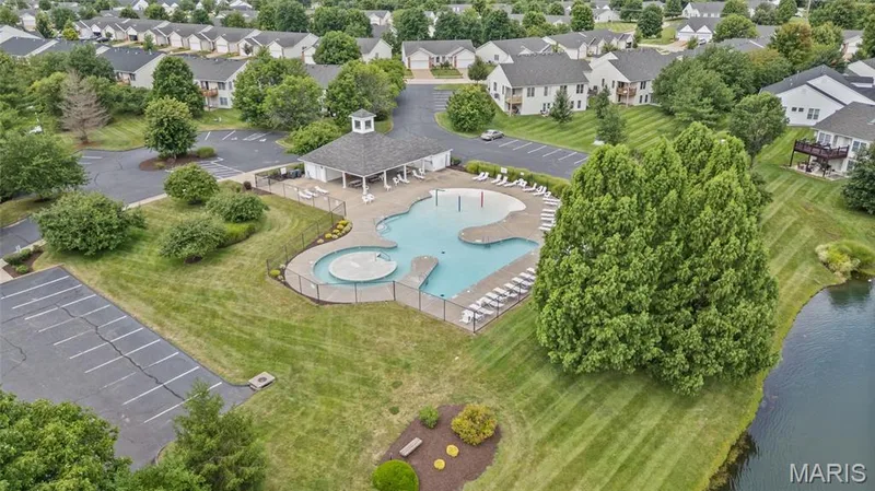 Community pool with an integrated spa, surrounded by a metal fence and lounge chairs — 195 England Drive, O'Fallon, MO 63366