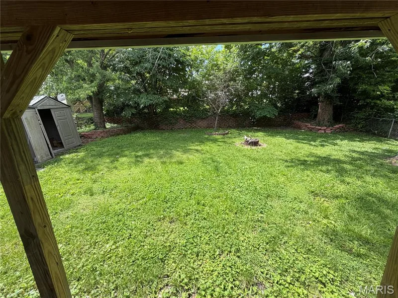 Expansive backyard featuring a level, well-groomed lawn bordered by mature trees and natural woodland — 2505 Ambelwood Lane, O'Fallon, MO 63368