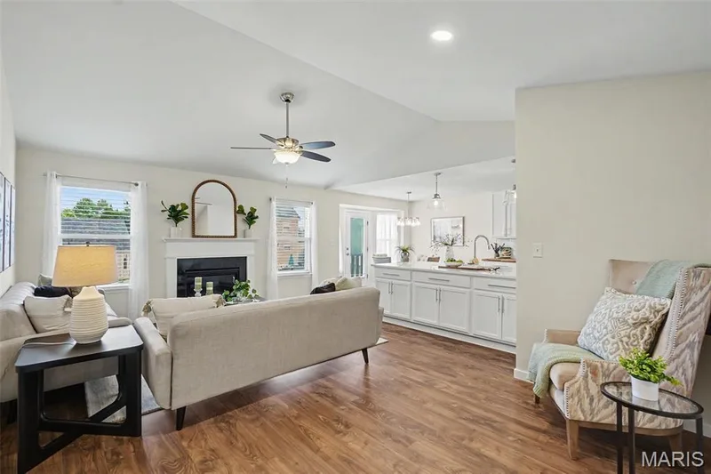 Open great room featuring a vaulted ceiling, LVP flooring, and a cozy gas fireplace — 18 Sonnet Way Court, Wentzville, MO 63385