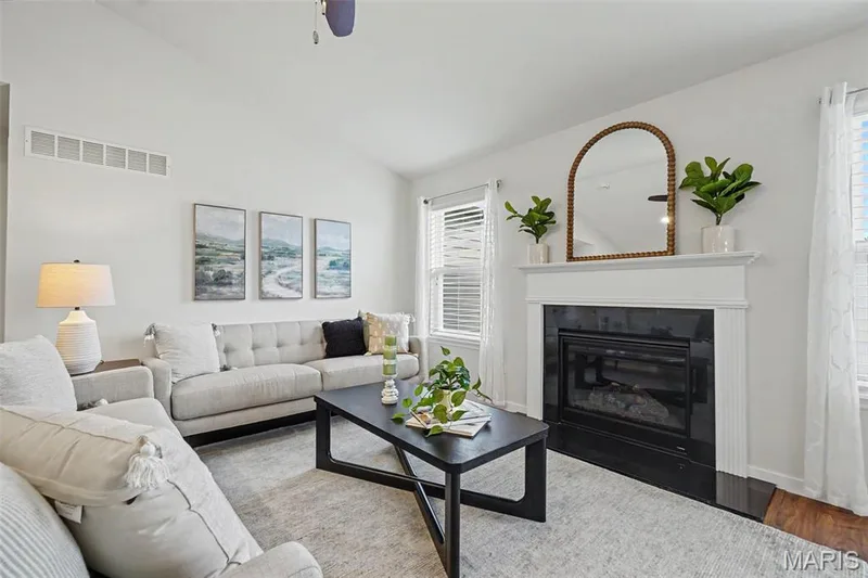Open great room featuring a vaulted ceiling, LVP flooring, and a cozy gas fireplace — 18 Sonnet Way Court, Wentzville, MO 63385