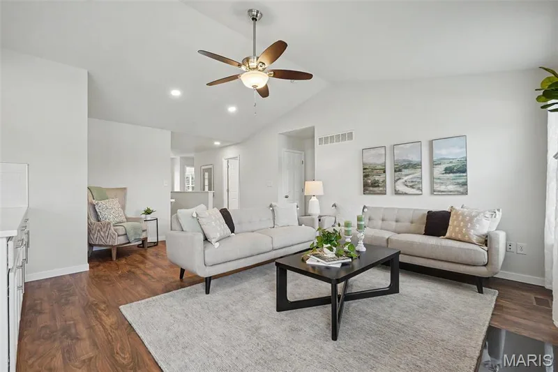 Open great room featuring a vaulted ceiling, LVP flooring, and a cozy gas fireplace — 18 Sonnet Way Court, Wentzville, MO 63385