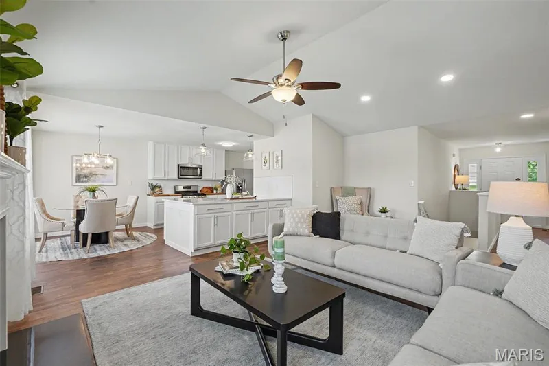 Open great room into the kitchen featuring a vaulted ceiling, LVP flooring, and a cozy gas fireplace — 18 Sonnet Way Court, Wentzville, MO 63385