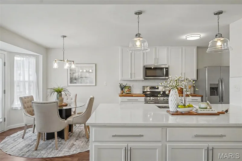 Fresh, bright, open kitchen featuring a custom oversized island with abundant storage, quartz countertops, SS appliances, and a walk-in pantry — 18 Sonnet Way Court, Wentzville, MO 63385