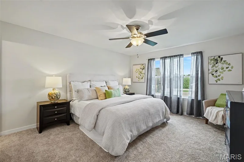 Spacious primary bedroom featuring new neutral plush carpeting and a ceiling fan — 18 Sonnet Way Court, Wentzville, MO 63385