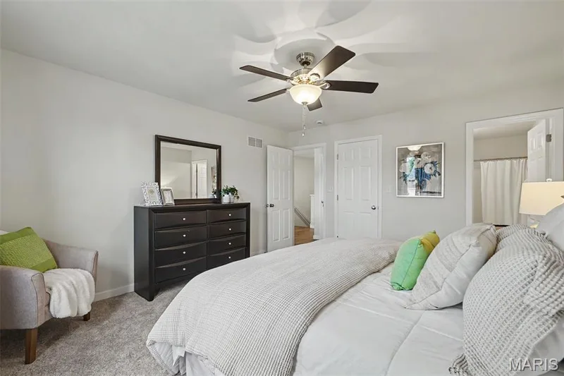 Spacious primary bedroom featuring new neutral plush carpeting and a ceiling fan — 18 Sonnet Way Court, Wentzville, MO 63385
