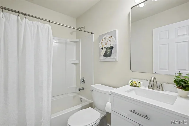 Renovated main-floor hall bath with ceramic tile flooring, new vanity, mirror, lighting, and an elongated commode — 18 Sonnet Way Court, Wentzville, MO 63385