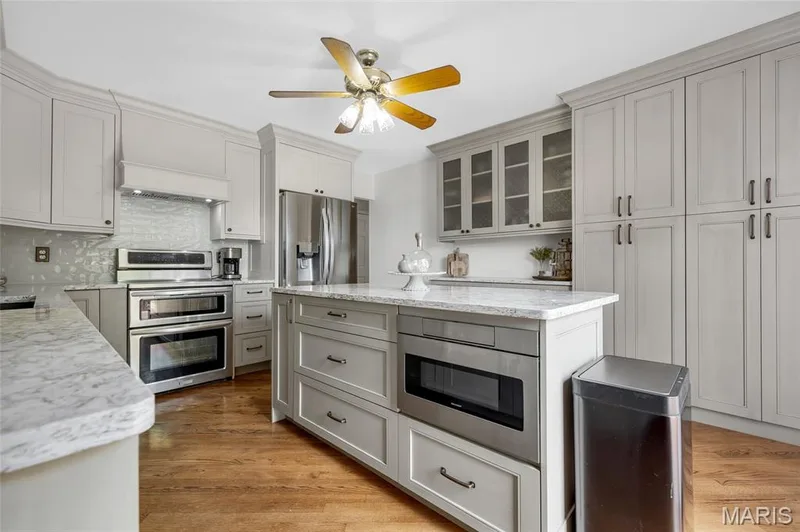Completely remodeled kitchen featuring custom  42" cabinetry with large storage drawers, hood, Cambria quartz countertops, island, quartz sink, drawer microwave, 3 rack dishwasher, refrigerator featuring craft ice maker, double oven range — 16 La Rochelle Court, Lake St. Louis, MO 63367