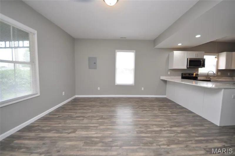 Open-concept living space featuring wood-finish flooring, recessed lighting, and a kitchen island with stone countertops — 502 S Linn Avenue, Wentzville, MO 63385