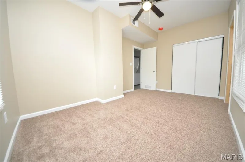 Spacious room featuring neutral carpeting, light-toned walls, and white baseboards — 502 S Linn Avenue, Wentzville, MO 63385