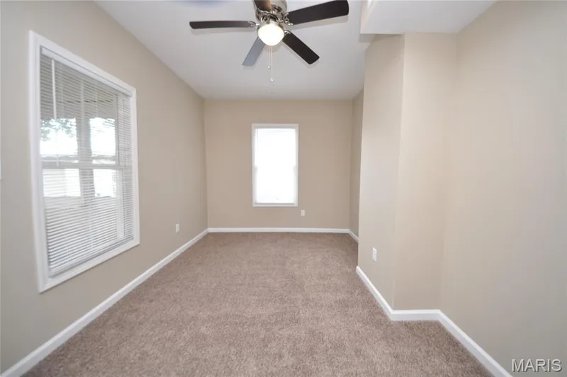 Room featuring neutral-toned walls, textured carpeting, and multiple windows — 502 S Linn Avenue, Wentzville, MO 63385
