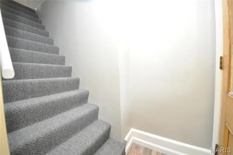 Staircase with gray textured carpeting, white handrail, and light wood-finish flooring — 502 S Linn Avenue, Wentzville, MO 63385