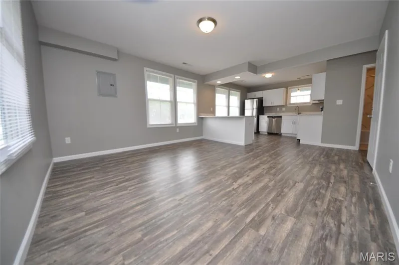 Open-concept living area featuring wood-finish flooring, recessed lighting, and a kitchen with white cabinetry — 502 S Linn Avenue, Wentzville, MO 63385