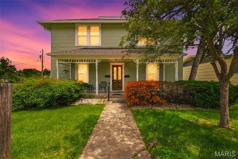 Green siding exterior featuring a covered porch with decorative white columns — 502 S Linn Avenue, Wentzville, MO 63385