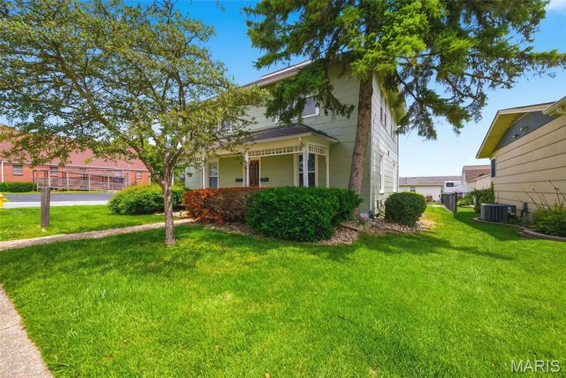 Light green two-story exterior with white trim and a covered front porch featuring a bay window — 502 S Linn Avenue, Wentzville, MO 63385