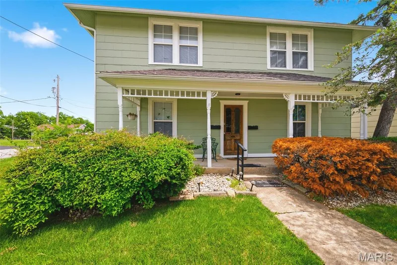Light green siding residence with a covered porch featuring decorative white columns and lattice work — 502 S Linn Avenue, Wentzville, MO 63385
