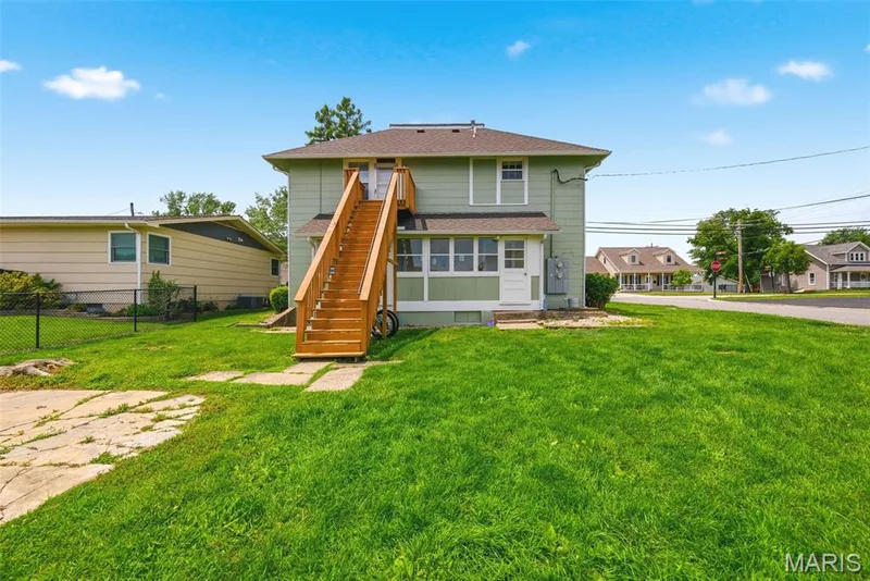 Two-story residence featuring light green siding and a prominent exterior staircase with wood railings — 502 S Linn Avenue, Wentzville, MO 63385