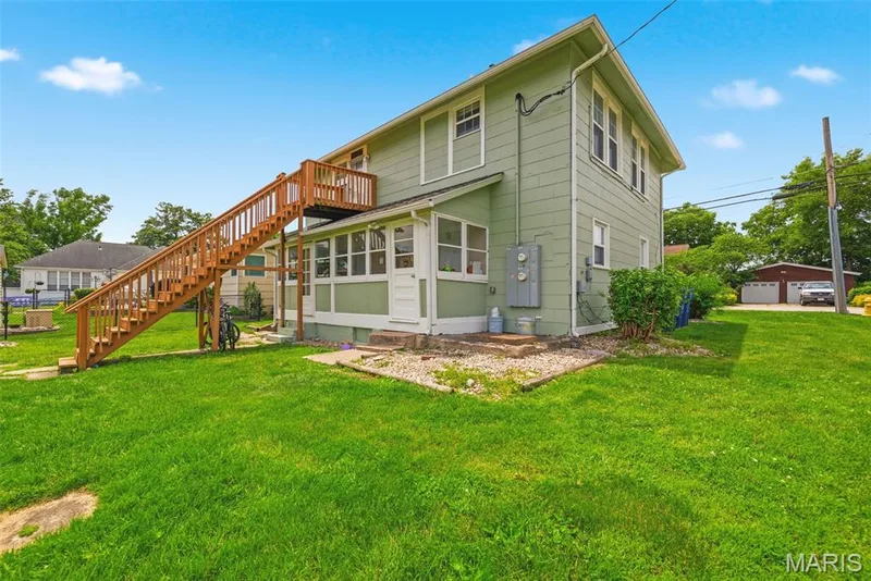 Rear exterior featuring a sunroom, a second-story wood deck, and a wooden staircase — 502 S Linn Avenue, Wentzville, MO 63385