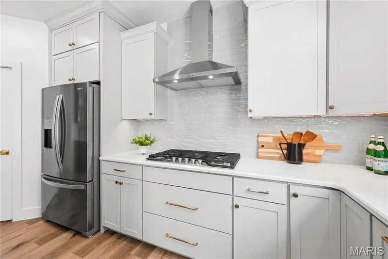 Gas Cooktop with Stainless Steel Chimney Hood and Refrigerator in Kitchen — 527 Ryehill Drive, St Peters, MO 63376