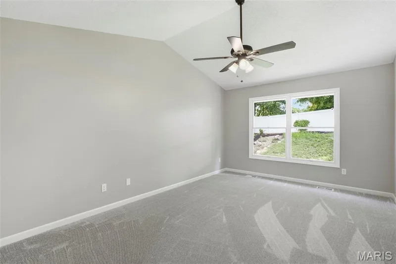 Vaulted ceiling with ceiling fan, light gray wall paint, light gray carpet, and a large double window — 814 Emerald Place Drive, St Charles, MO 63304