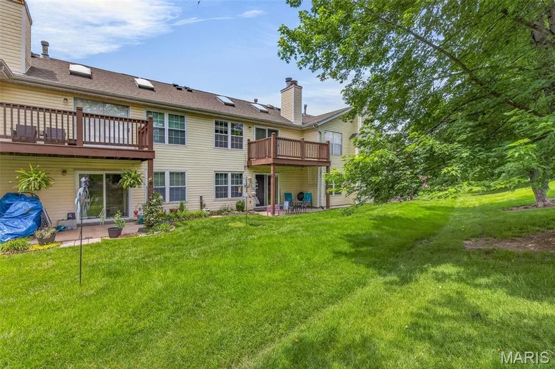 Rear exterior featuring two levels of outdoor living space, including a raised wood deck and a ground-level patio — 1034 Windstream Drive #14, St Peters, MO 63376