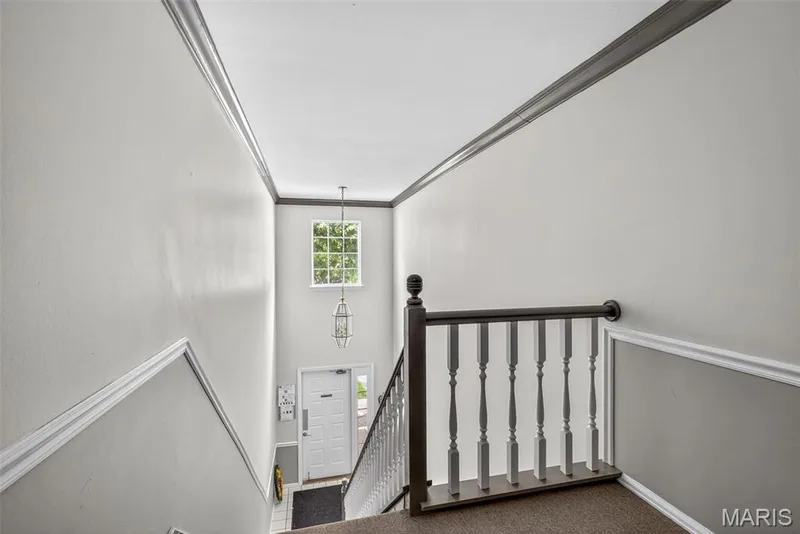 Two-story foyer featuring an overhead window, a hanging lantern pendant light, and a white paneled entry door — 1034 Windstream Drive #14, St Peters, MO 63376