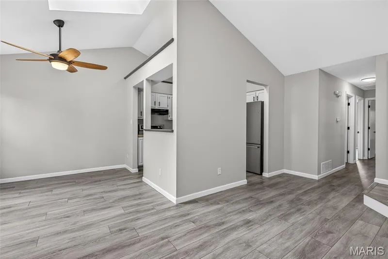 Spacious living area featuring wood-finish flooring, vaulted ceilings, and a modern ceiling fan — 1034 Windstream Drive #14, St Peters, MO 63376