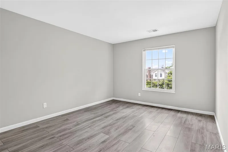 Interior room featuring light grey wall paint, wood-finish flooring, white trim, and a white-framed window — 1034 Windstream Drive #14, St Peters, MO 63376