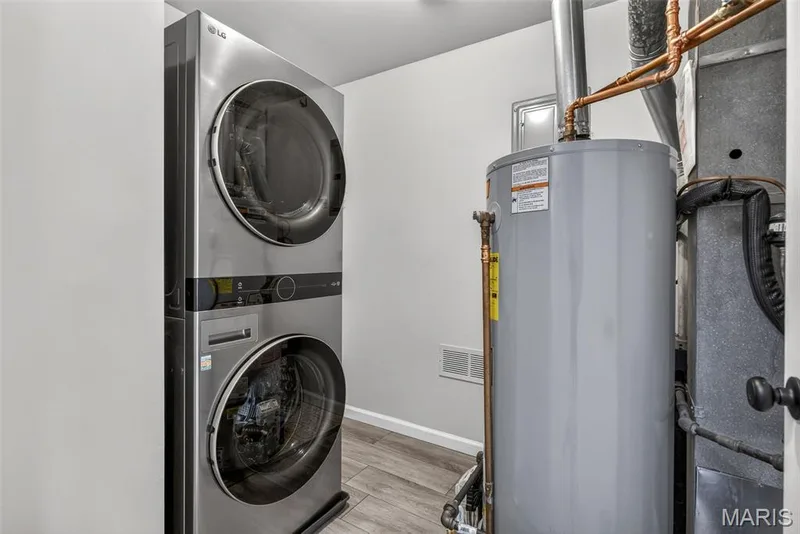Dedicated utility area featuring a stacked washer and dryer unit, water heater, and HVAC system — 1034 Windstream Drive #14, St Peters, MO 63376