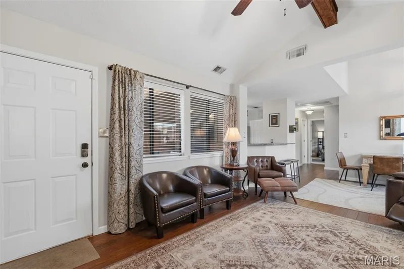 Open concept living area featuring vaulted ceilings, wood-finish flooring, and multiple windows with blinds — 704 Hemingway Lane #E, Weldon Spring, MO 63304