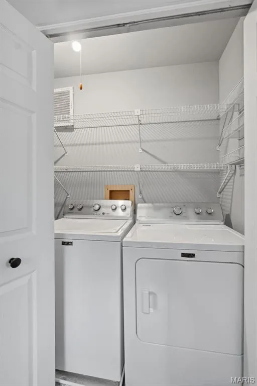 Dedicated laundry area featuring a washer and dryer, overhead wire shelving, and a pull-chain light fixture — 704 Hemingway Lane #E, Weldon Spring, MO 63304
