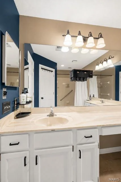 Bathroom vanity featuring a light-toned countertop, an integrated sink, and white cabinetry with dark hardware — 704 Hemingway Lane #E, Weldon Spring, MO 63304