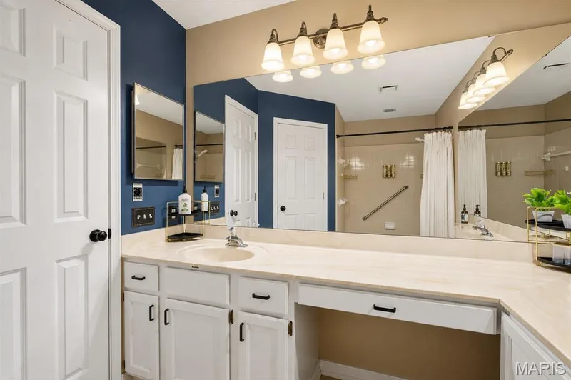 Bathroom vanity featuring double sink and linen closet — 704 Hemingway Lane #E, Weldon Spring, MO 63304