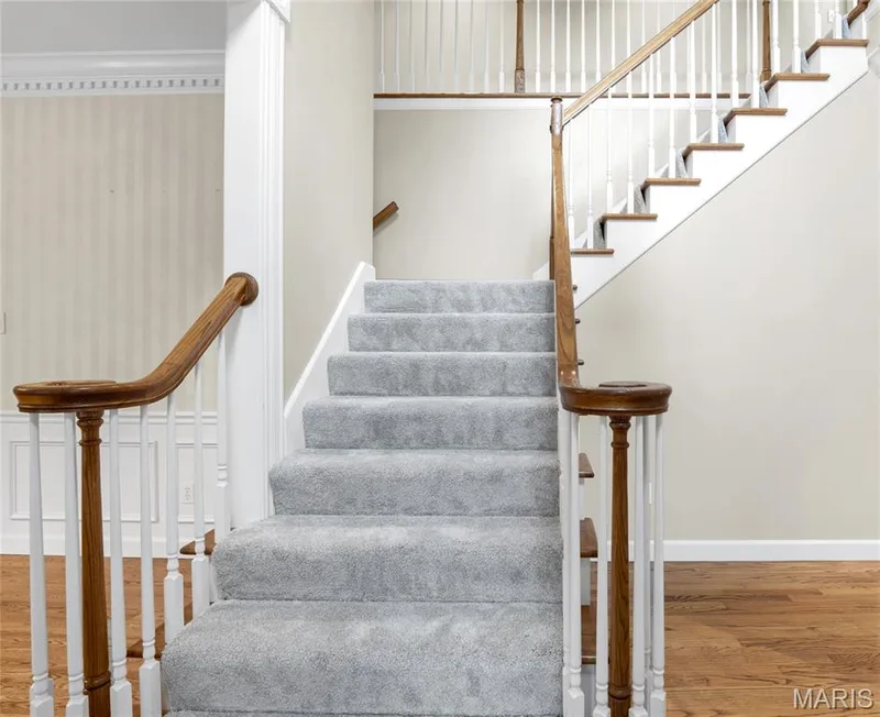 Staircase featuring wood handrails, white balusters, and grey carpeting — 2154 White Lane Drive, Chesterfield, MO 63017