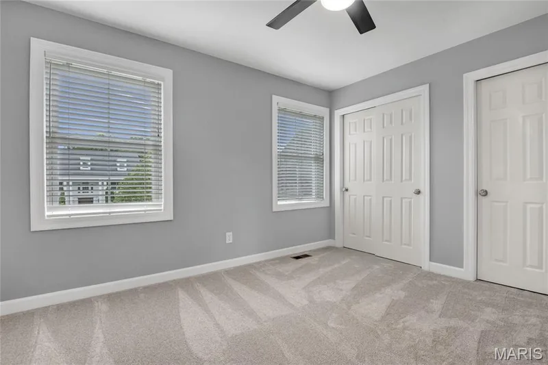 4th Bedroom with Jack-n-Jill Bathroom. Carpeted flooring, ceiling fan with integrated lighting, two windows with blinds, and two solid panel closet doors — 2154 White Lane Drive, Chesterfield, MO 63017
