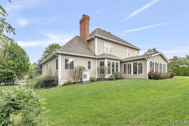 Expansive green lawn, multi-pane bay window, sunroom with multiple windows, brick chimney, and black metal fencing — 2154 White Lane Drive, Chesterfield, MO 63017