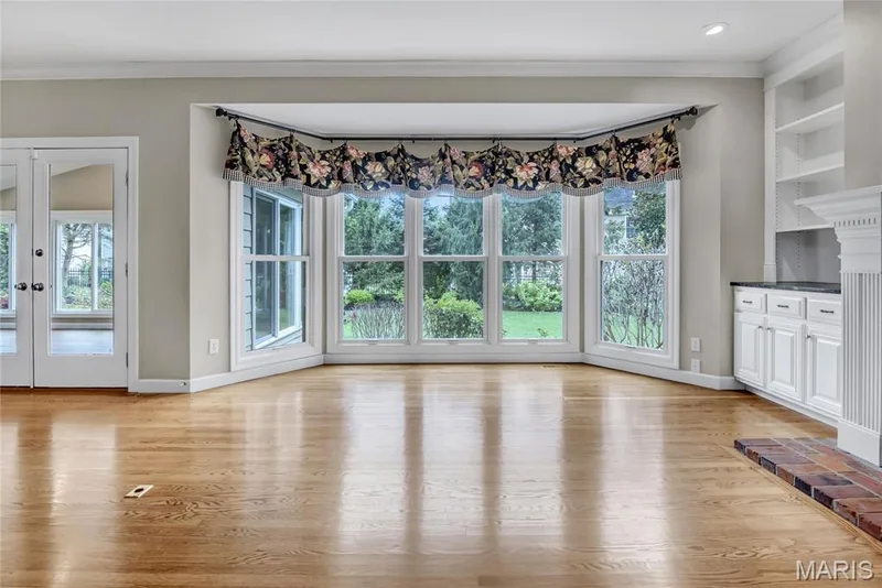 Hardwood flooring, bay window, built-in shelving, white cabinetry with dark countertop, and a brick fireplace hearth — 2154 White Lane Drive, Chesterfield, MO 63017